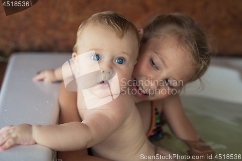 Image of Two happy little children playing in the bath at the day time.