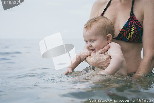 Image of Mother and baby son playing on the beach at the day time.