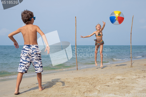 Image of Two happy little children playing on the beach at the day time.