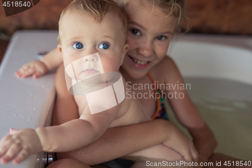 Image of Two happy little children playing in the bath at the day time.