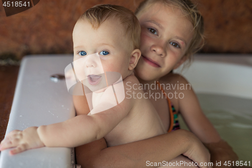 Image of Two happy little children playing in the bath at the day time.