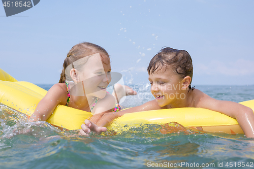 Image of Two happy little children playing on the beach at the day time.