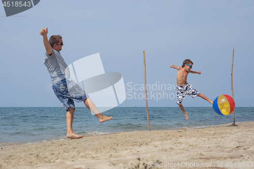 Image of Father and son playing football on the beach