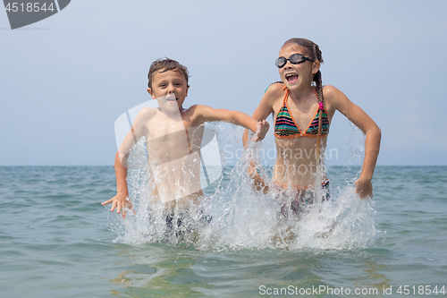 Image of Two happy little children playing on the beach at the day time.