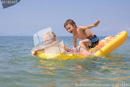 Image of Two happy little children playing on the beach at the day time.