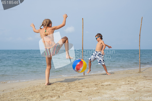 Image of Two happy little children playing on the beach at the day time.