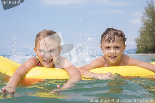 Image of Two happy little children playing on the beach at the day time.