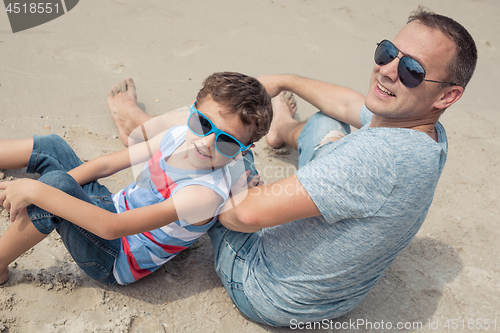 Image of Father and son playing on the beach at the day time.