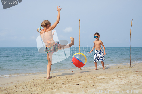 Image of Two happy little children playing on the beach at the day time.