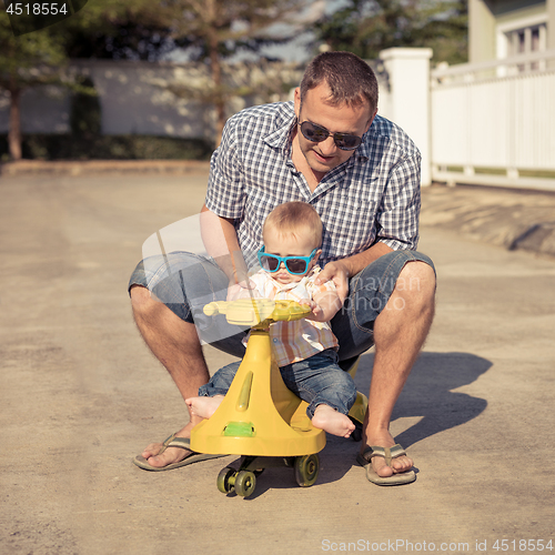 Image of Father and baby son playing on the road at the day time.