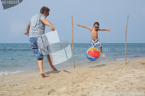 Image of Father and son playing football on the beach