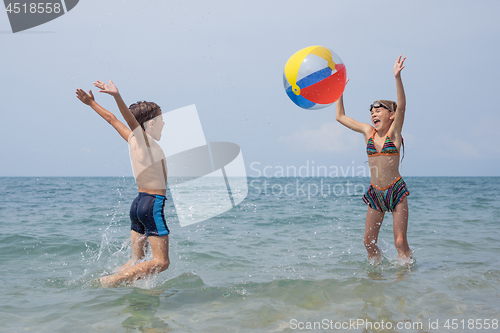 Image of Two happy little children playing on the beach at the day time.