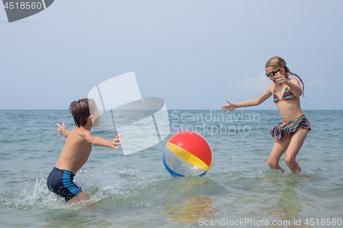 Image of Two happy little children playing on the beach at the day time.