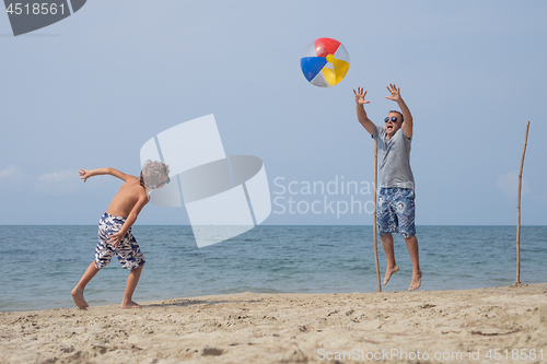 Image of Father and son playing football on the beach