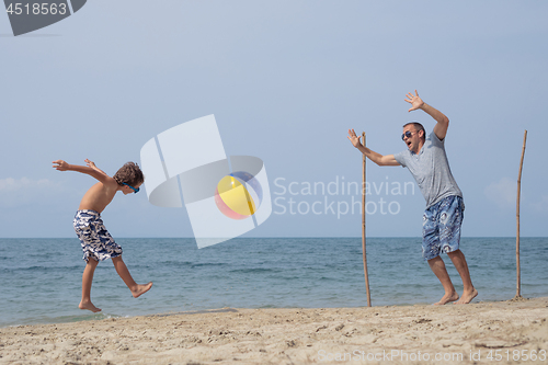 Image of Father and son playing football on the beach