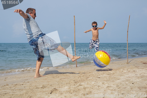 Image of Father and son playing football on the beach