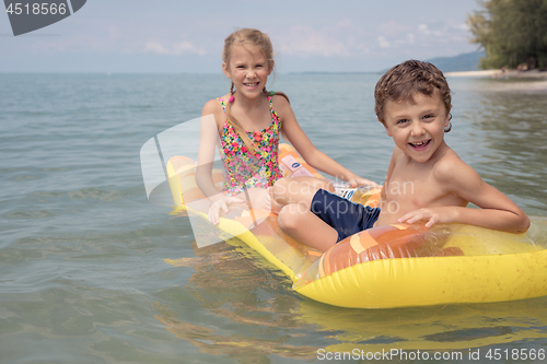 Image of Two happy little children playing on the beach at the day time.