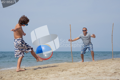 Image of Father and son playing football on the beach