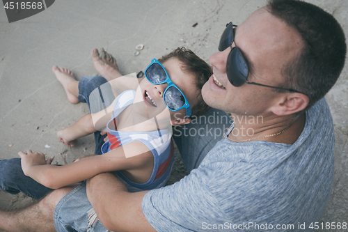 Image of Father and son playing on the beach at the day time.