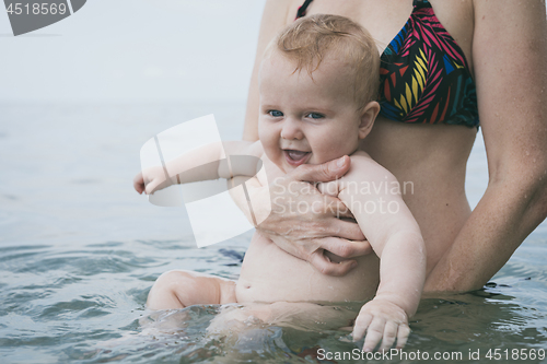 Image of Mother and baby son playing on the beach at the day time. 