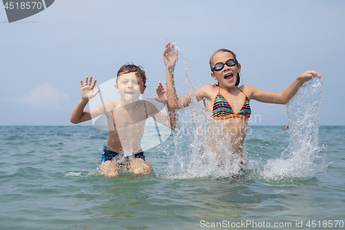 Image of Two happy little children playing on the beach at the day time.