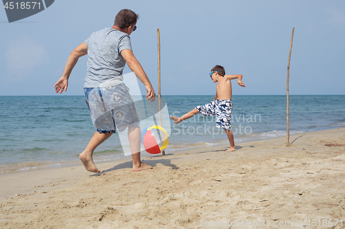 Image of Father and son playing football on the beach