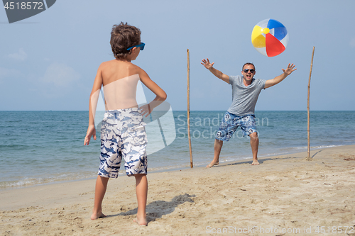 Image of Father and son playing football on the beach