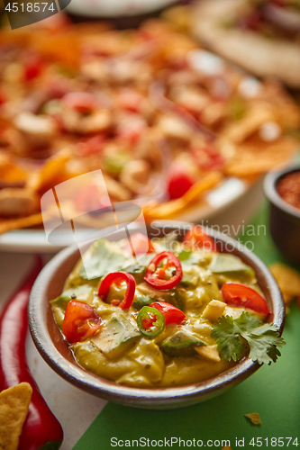 Image of Close up on guacamole dip in bowl with various freshly made Mexican foods