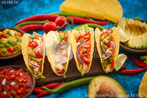 Image of Mexican taco with chicken meat, jalapeno, fresh vegetables served with guacamole