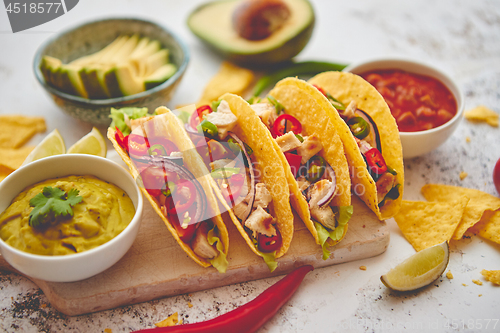 Image of Tasty Mexican meat tacos served with various vegetables and salsa