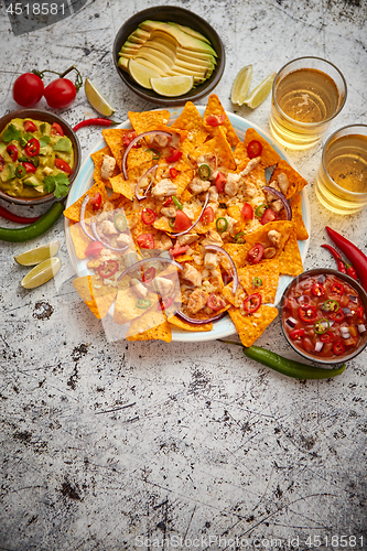 Image of A plate of delicious tortilla nachos with melted cheese sauce, grilled chicken