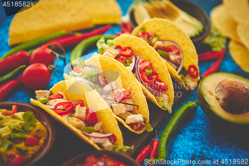 Image of Mexican taco with chicken meat, jalapeno, fresh vegetables served with guacamole