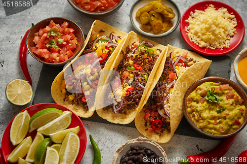 Image of Tasty Mexican meat tacos served with various vegetables and salsa