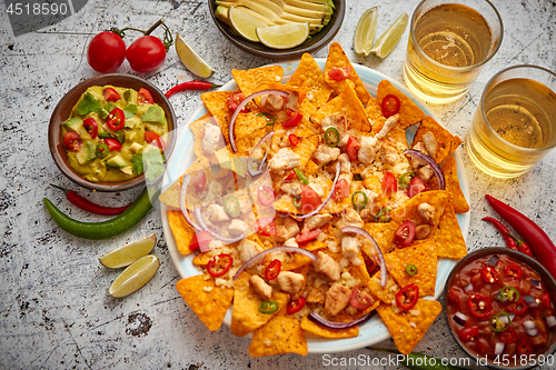 Image of A plate of delicious tortilla nachos with melted cheese sauce, grilled chicken