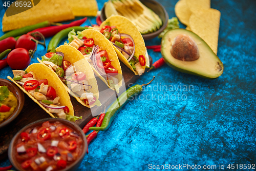 Image of Mexican taco with chicken meat, jalapeno, fresh vegetables served with guacamole