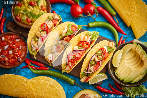 Image of Mexican taco with chicken meat, jalapeno, fresh vegetables served with guacamole