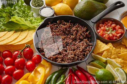 Image of Ingredients for Chili con carne in frying iron pan on white wooden table