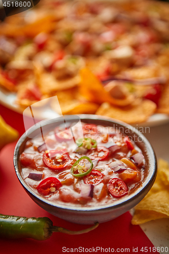Image of Close up on hot tomato dip in ceramic bowl with various freshly made Mexican foods