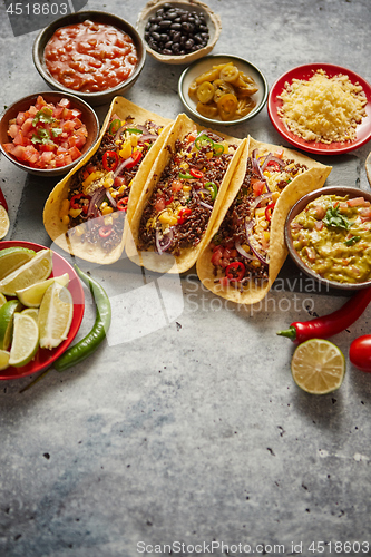 Image of Tasty Mexican meat tacos served with various vegetables and salsa