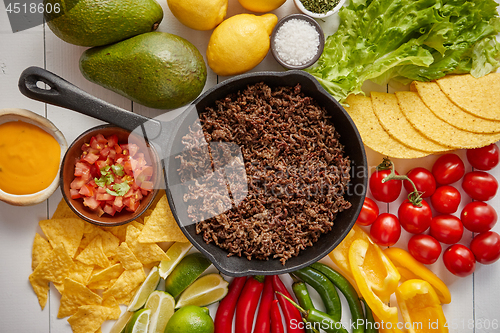 Image of Ingredients for Chili con carne in frying iron pan on white wooden table