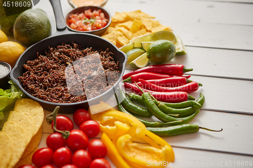 Image of Ingredients for Chili con carne in frying iron pan on white wooden table