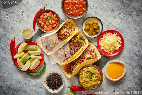 Image of Tasty Mexican meat tacos served with various vegetables and salsa