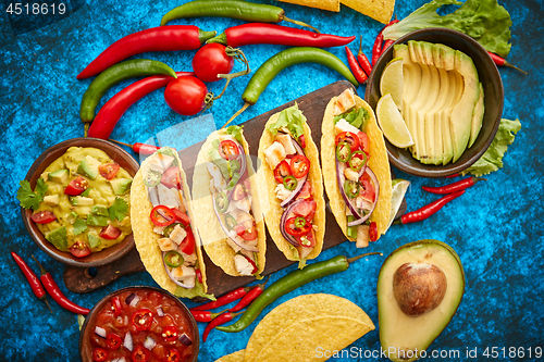 Image of Mexican taco with chicken meat, jalapeno, fresh vegetables served with guacamole