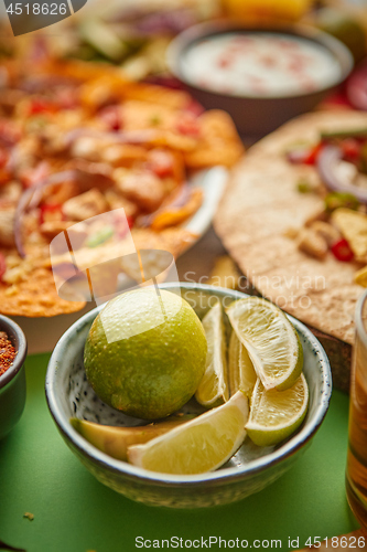 Image of Close up on lime slices in ceramic bowl with various freshly made Mexican foods