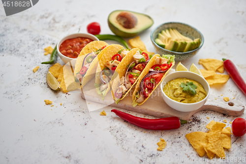 Image of Tasty Mexican meat tacos served with various vegetables and salsa