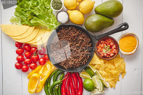 Image of Ingredients for Chili con carne in frying iron pan on white wooden table