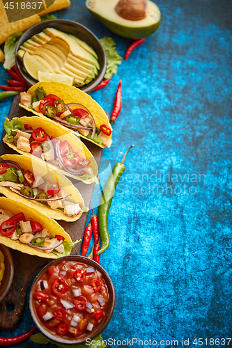 Image of Mexican taco with chicken meat, jalapeno, fresh vegetables served with guacamole