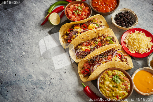 Image of Tasty Mexican meat tacos served with various vegetables and salsa