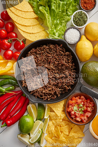 Image of Ingredients for Chili con carne in frying iron pan on white wooden table