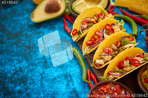 Image of Mexican taco with chicken meat, jalapeno, fresh vegetables served with guacamole